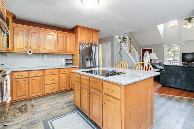 kitchen featuring black electric cooktop, a center island, hardwood / wood-style floors, stainless steel fridge with ice dispenser, and ceiling fan