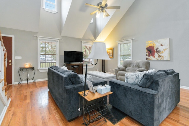 living room featuring a towering ceiling, ceiling fan, and light hardwood / wood-style flooring