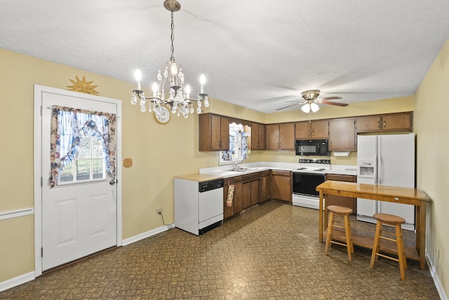 kitchen featuring white appliances, ceiling fan with notable chandelier, sink, hanging light fixtures, and a textured ceiling