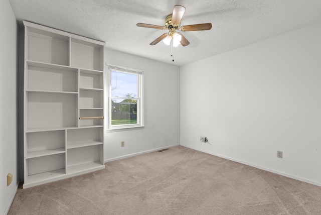 carpeted empty room with ceiling fan and a textured ceiling