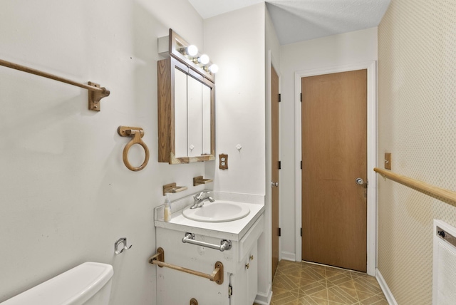 bathroom with tile patterned floors, vanity, a textured ceiling, and toilet