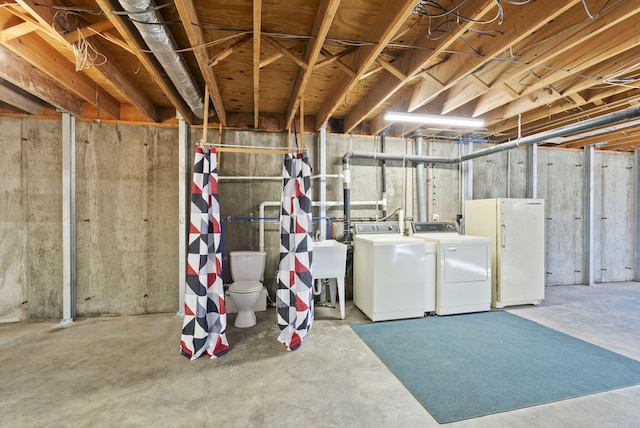 basement with washing machine and dryer, white refrigerator, and sink