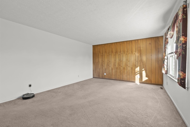 carpeted spare room featuring a textured ceiling and wood walls