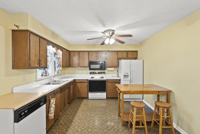 kitchen featuring a textured ceiling, white appliances, ceiling fan, and sink