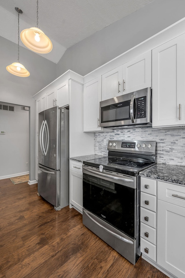 kitchen featuring white cabinetry, appliances with stainless steel finishes, tasteful backsplash, dark wood-type flooring, and vaulted ceiling