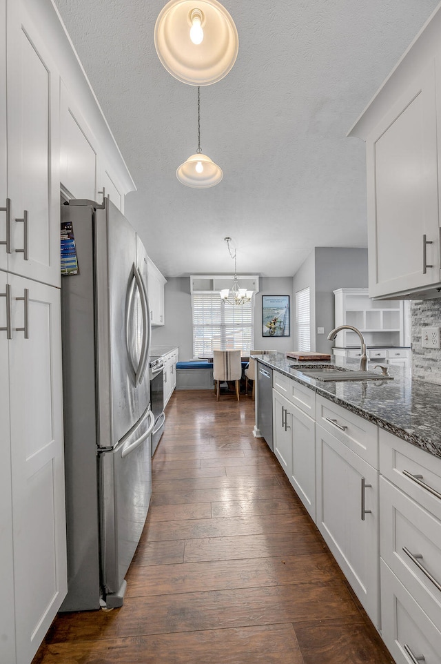 kitchen featuring white cabinets, stainless steel appliances, pendant lighting, and dark hardwood / wood-style flooring