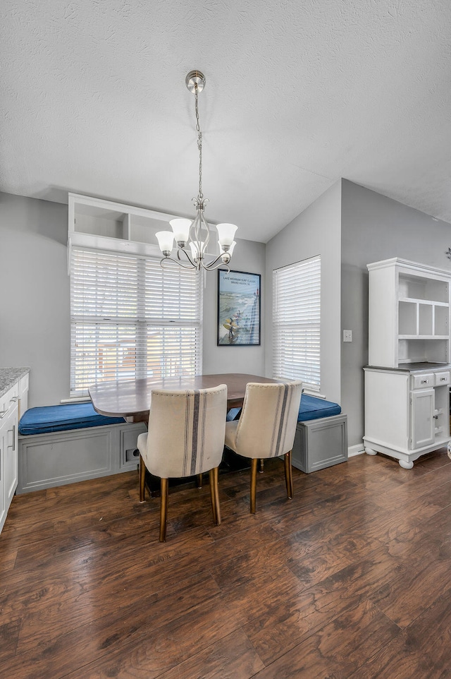 dining room with lofted ceiling, a textured ceiling, dark hardwood / wood-style flooring, and a notable chandelier