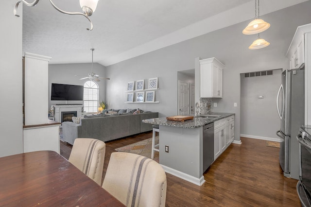 kitchen featuring a kitchen bar, dark stone countertops, white cabinetry, and appliances with stainless steel finishes