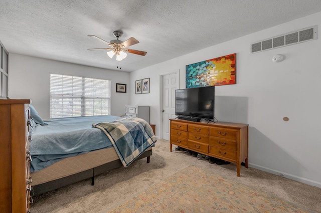 bedroom featuring ceiling fan, a textured ceiling, and light carpet