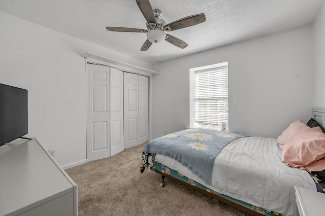 carpeted bedroom with ceiling fan, a textured ceiling, and a closet