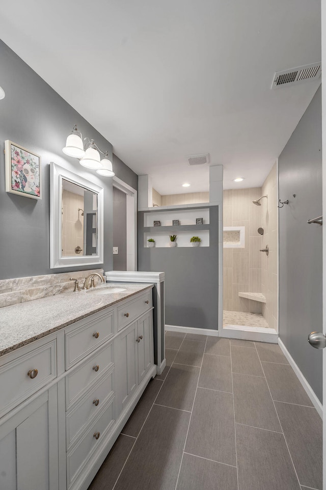 bathroom featuring vanity, tile patterned floors, and a tile shower