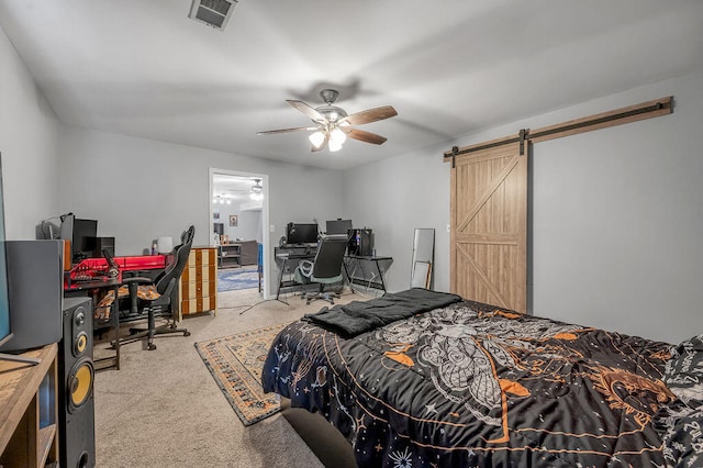 carpeted bedroom with a barn door and ceiling fan