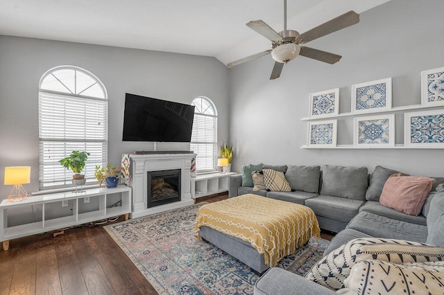 living room featuring dark hardwood / wood-style flooring, ceiling fan, and vaulted ceiling