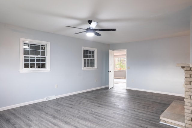 empty room with dark hardwood / wood-style flooring, ceiling fan, and a fireplace