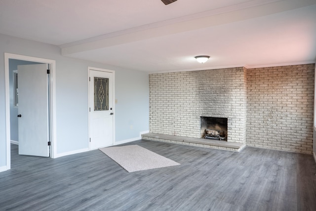 unfurnished living room featuring a brick fireplace, brick wall, and dark hardwood / wood-style floors