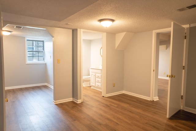 additional living space featuring wood-type flooring and a textured ceiling