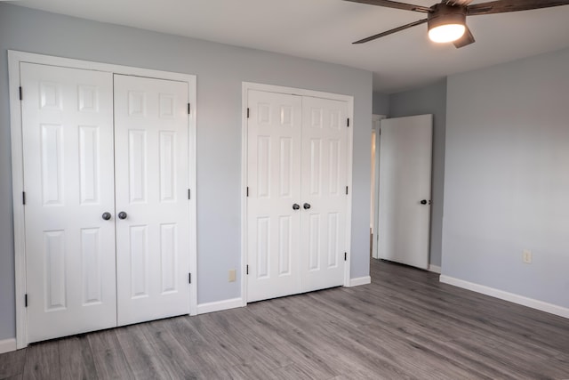 unfurnished bedroom with multiple closets, hardwood / wood-style floors, and ceiling fan