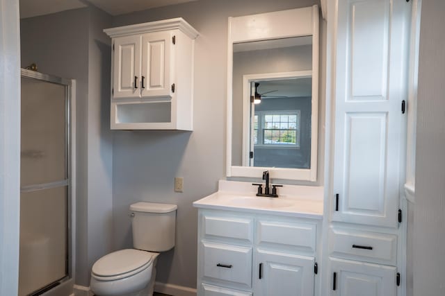 bathroom with ceiling fan, a shower with door, vanity, and toilet