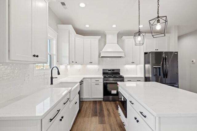 kitchen featuring light countertops, appliances with stainless steel finishes, white cabinetry, premium range hood, and dark wood-style flooring