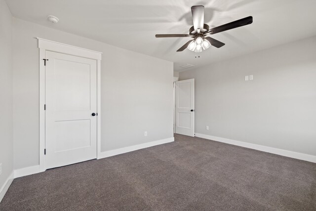 spare room featuring ceiling fan, baseboards, dark colored carpet, and visible vents