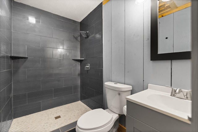 bathroom featuring toilet, tiled shower, and vanity