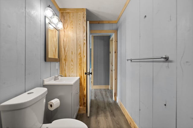 bathroom with toilet, vanity, ornamental molding, and hardwood / wood-style floors