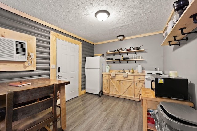 kitchen with a textured ceiling, white fridge, light brown cabinetry, light hardwood / wood-style flooring, and crown molding