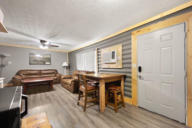 dining space with ceiling fan, a textured ceiling, an AC wall unit, and light wood-type flooring