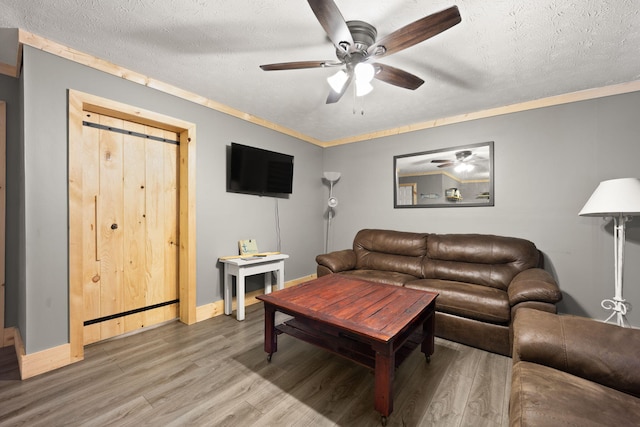 living room with ceiling fan, hardwood / wood-style floors, ornamental molding, and a textured ceiling