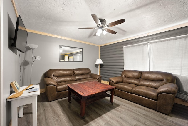 living room with a textured ceiling, ceiling fan, ornamental molding, and wood-type flooring