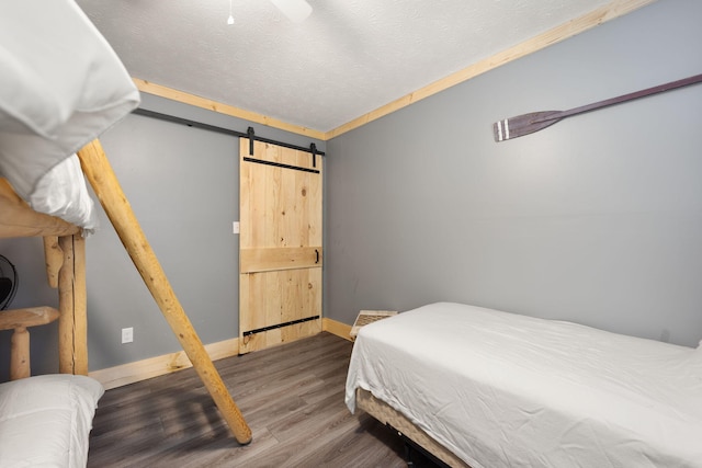 bedroom featuring hardwood / wood-style flooring, ceiling fan, crown molding, and a barn door