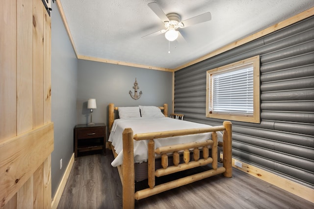 bedroom featuring a barn door, ceiling fan, dark hardwood / wood-style floors, a textured ceiling, and crown molding