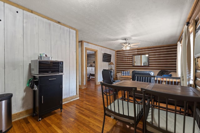 dining area featuring ceiling fan, dark wood-type flooring, a textured ceiling, and ornamental molding