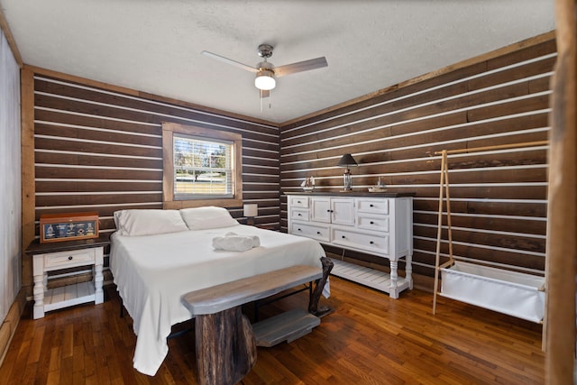 bedroom with a textured ceiling, ceiling fan, and dark wood-type flooring