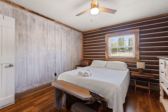 bedroom with ceiling fan, dark hardwood / wood-style floors, and wooden walls