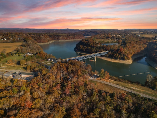 aerial view at dusk featuring a water view