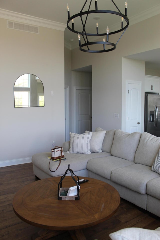 living room featuring dark wood-type flooring, a chandelier, and crown molding