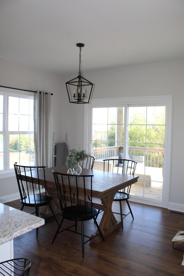 dining area featuring a wealth of natural light, dark hardwood / wood-style floors, and a chandelier