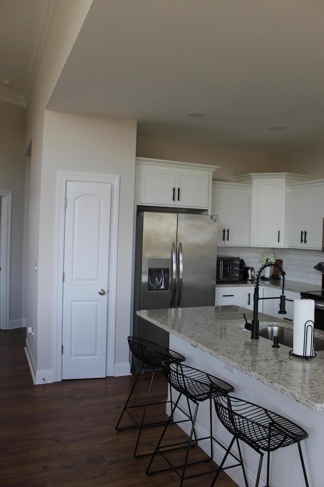 kitchen with white cabinets, sink, dark hardwood / wood-style floors, a breakfast bar, and light stone countertops