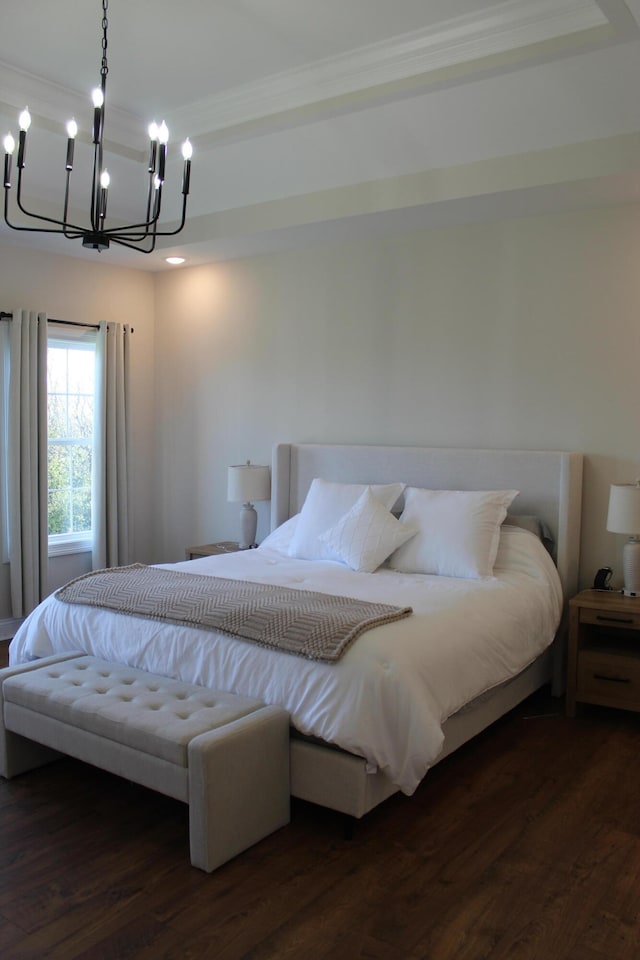 bedroom with dark wood-type flooring, a notable chandelier, and ornamental molding