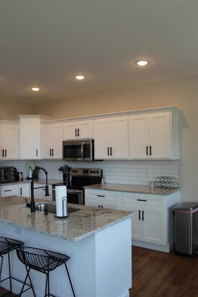 kitchen with tasteful backsplash, white cabinetry, dark hardwood / wood-style floors, and stainless steel appliances