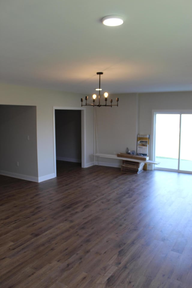 unfurnished room featuring dark wood-type flooring and a chandelier