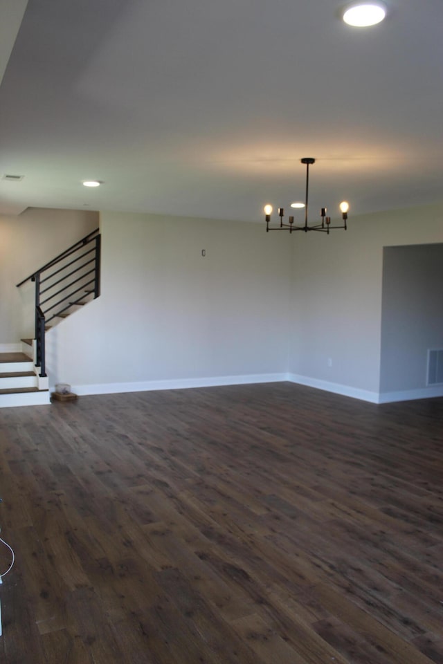 empty room featuring dark wood-type flooring and a chandelier