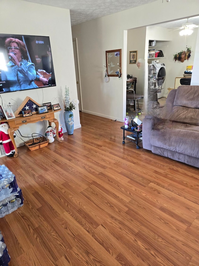 living room with washer / clothes dryer, hardwood / wood-style floors, ceiling fan, and a textured ceiling