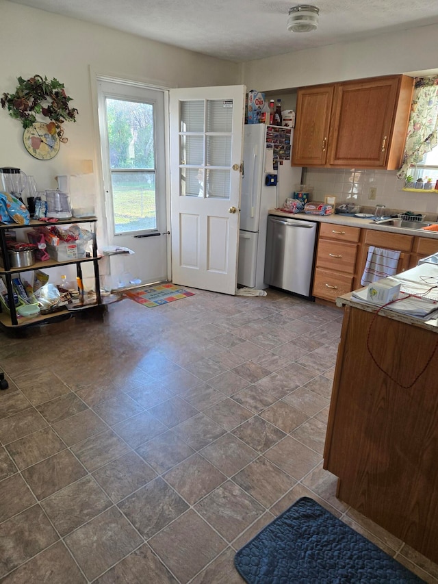 kitchen with stainless steel dishwasher, white refrigerator, and decorative backsplash