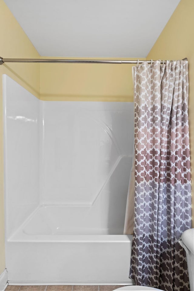 bathroom featuring tile patterned flooring, toilet, and shower / bath combo with shower curtain