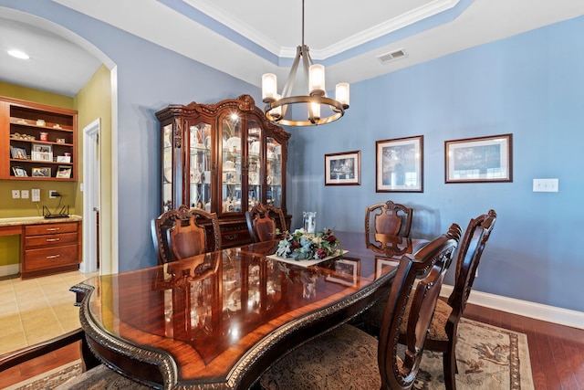 dining area featuring a tray ceiling, arched walkways, visible vents, and built in study area