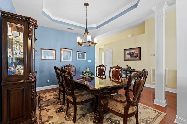 dining room with visible vents, dark wood-style flooring, a raised ceiling, and decorative columns