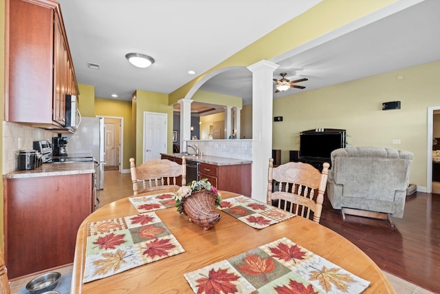 dining area with visible vents, ceiling fan, light wood-style floors, arched walkways, and ornate columns