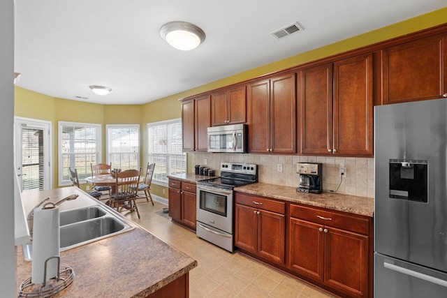 kitchen featuring baseboards, visible vents, a sink, decorative backsplash, and appliances with stainless steel finishes